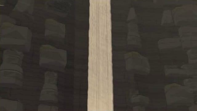 A tall waterfall blurred smooth by a long exposure against dark cliffs